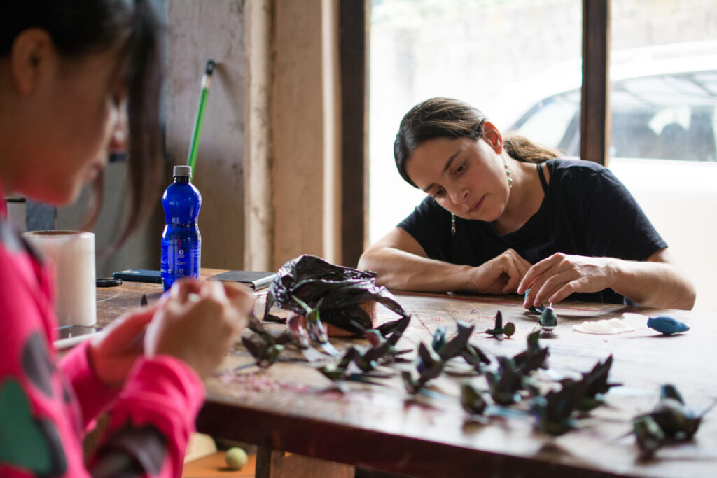 Women painting handcrafted colibri toys